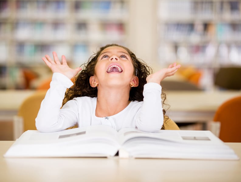 Excited schoolgirl at the library reading a book-1