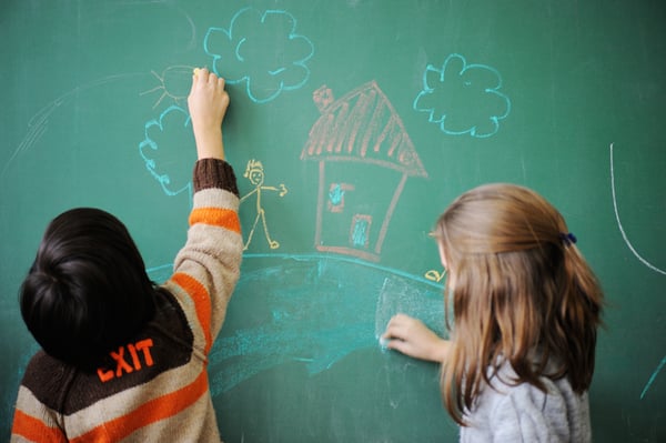 Two schoolkids wriing on blackboard