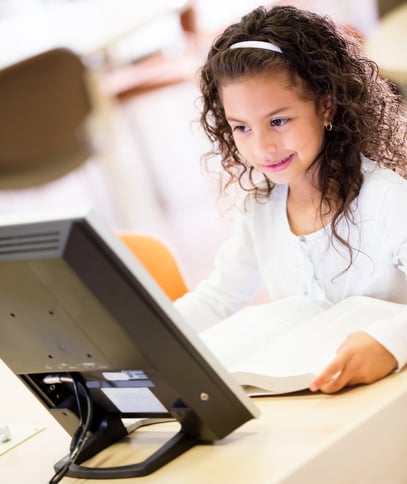 Young schoolgirl working on a computer at school